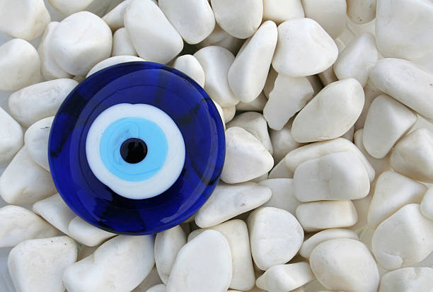 Blue and white evil eye amulet on small white rocks