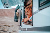 One female tourist enjoy view and freedom feeling inside a camper van vehicle looking outside the window. Concept of nomadic life and vanlife independent modern people. New tiny house style. Transport