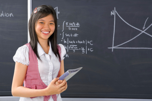 Female student pose in front of blackboard.