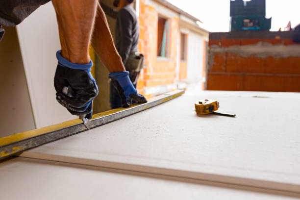 istock Worker cuts plaster with scalpel, measuring tape is set on gypsum board in workshop at building site 1477052290