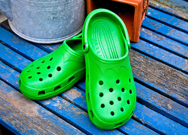 Green Garden Clogs On A Blue Table Green Garden Clogs On A Blue Table crocodile photos stock pictures, royalty-free photos & images