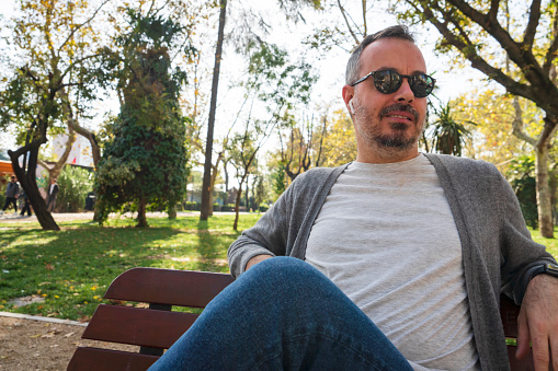 man relaxing sitting on a bench in a park