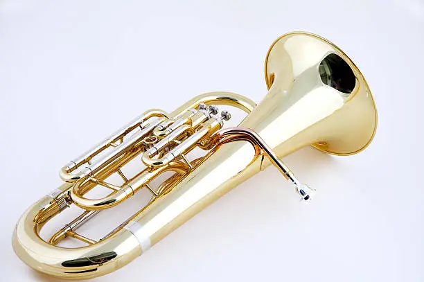 A complete gold brass tuba or euphonium isolated against a high key white background in the horizontal format with  copy space.