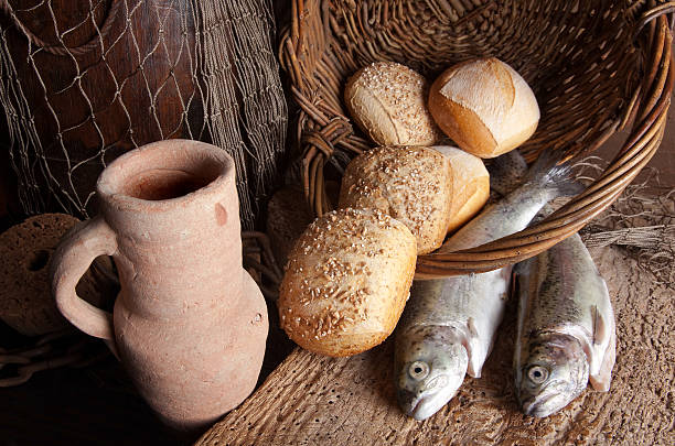 Wine jug with bread and fish Vintage still life of an old wine jug with bread loaves and fresh fish miracle stock pictures, royalty-free photos & images