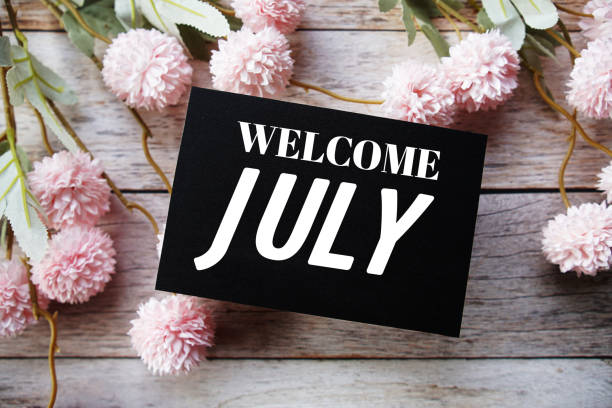 istock Welcome July text message with flower decoration on wooden background 1477062976