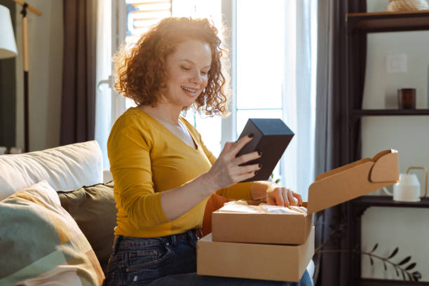 istock Smiling young woman unpacking cardboard box 1477063002