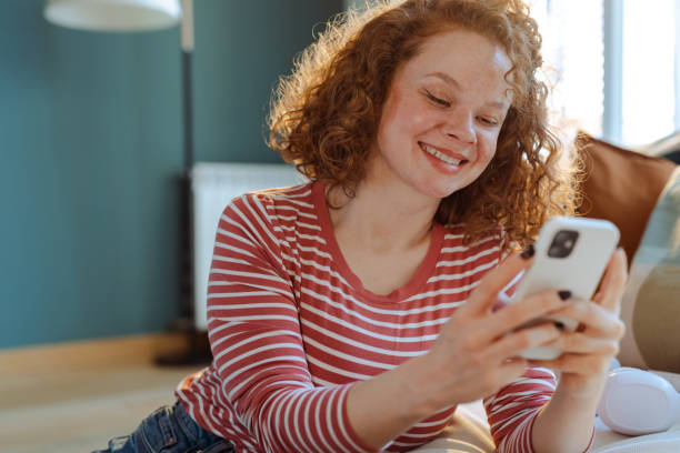 istock Beautiful redhead woman using smart phone at home 1477065871