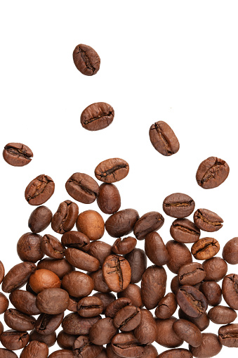 roasted whole arabica coffee beans, scattered on paper, isolated