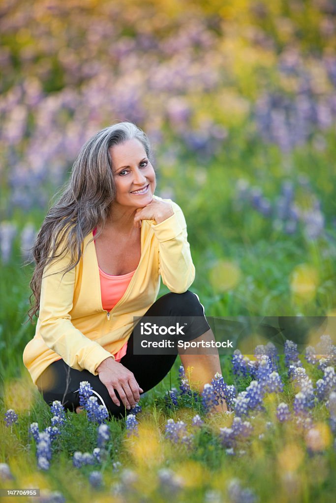 Среднего возраста женщина, сидящая в Техасе Bluebonnets - Стоковые фото Пожилой возраст роялти-фри