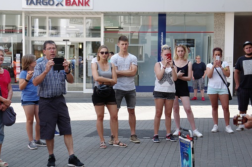 Trier, Germany - July 14, 2018.  People listening to a street musician  on a summer day in The Eifel region city of Trier.