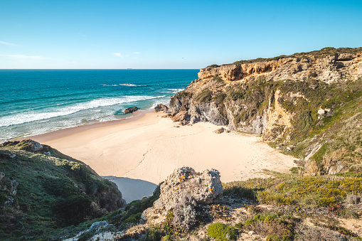 Breathtaking cliffs surround the sandy beach of Praia da Angra da Cerva on the Atlantic coast near Vila Nova de Milfontes, Odemira, Portugal. In the footsteps of Rota Vicentina. Fisherman trail.