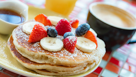 Belgian pancakes served with fruits and maple syrup.