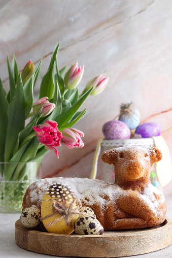 Easter cake in the shape of a lamb with Easter eggs and spring flowers on the table