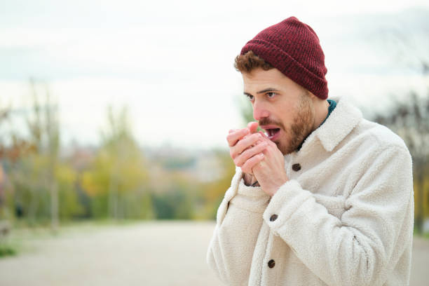 Latin young man rubbing his hands to warmth during winter. Cold weather. Flu.