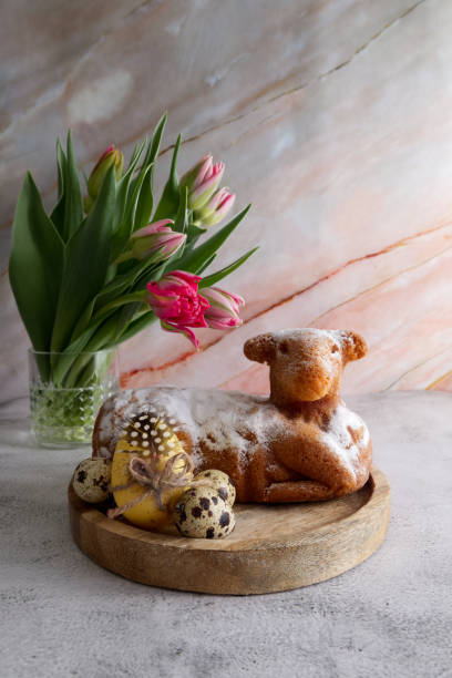 istock Easter cake in the shape of a lamb with Easter eggs and spring flowers on the table 1477081155