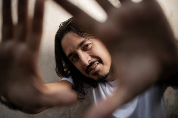 Portrait of a white long haired man, with beard, wearing a white shirt, interacting with the camera
