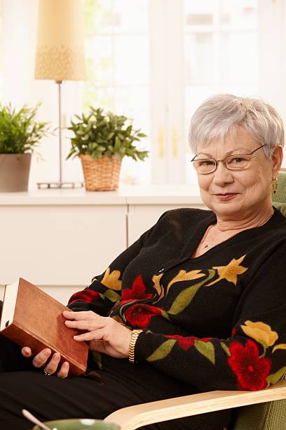 istock Elderly woman in armchair with book 147708302