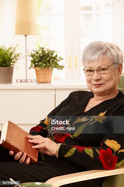 Foto de Idosos Mulher Na Poltrona Com Livro e mais fotos de stock de 60 Anos - 60 Anos, 60-64 anos, Aconchegante