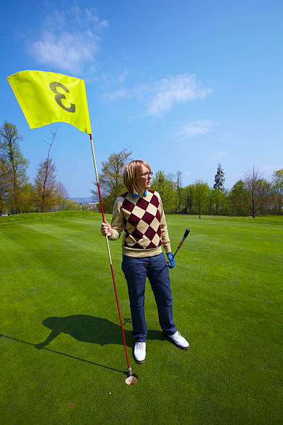 frau hält eine flagge auf golfplatz - golf golf course putting green hole stock-fotos und bilder