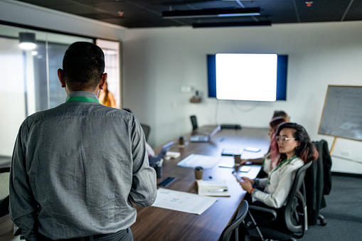 Rear view of a leader businessman talking to his employees at office