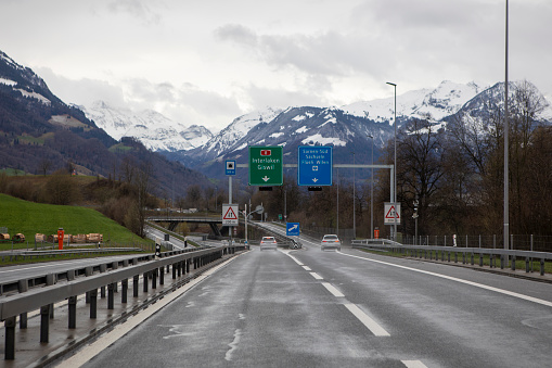 Sarnen, Switzerland; 26.03.2023: Driving cars on the road, road signs, road fok. Highway with Alps view. Transportation infrastructure, rural landscape and mountains, Swiss countryside.
