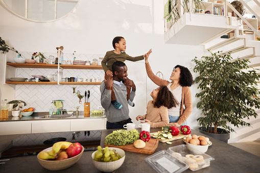 Happy African American family talking while having fun in the kitchen. Mother and son are giving each other high-five.