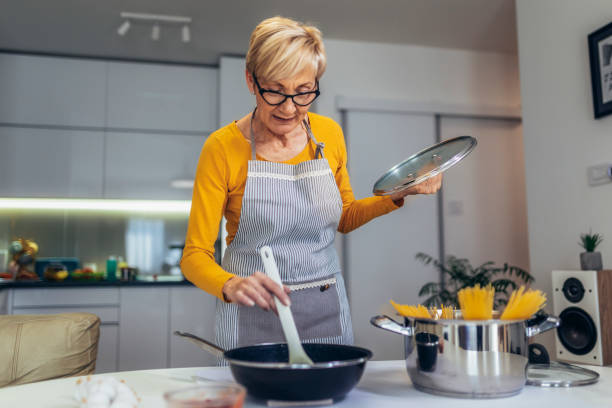 istock Happy senior woman cooking in her modern kitchen 1477085566