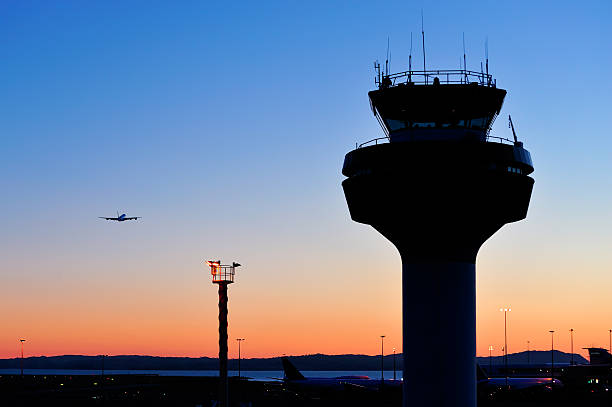 Air traffic control tower at sunset An Airbus A380 begins its ascent out of Auckland Airport. Set against a perfectly clear sunset sky, distance makes the flying behemoth look dwarfed by the traffic control tower in the foreground. air traffic control tower stock pictures, royalty-free photos & images