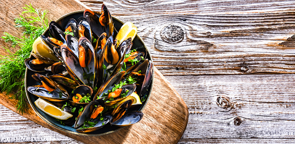 Composition with a plate of steamed mussels served with parsley and lemon