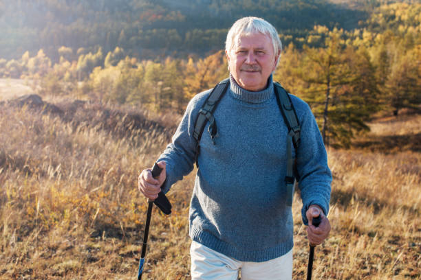 istock Attractive gray haired senior man hiking in forest using poles for nordic walking 1477087689