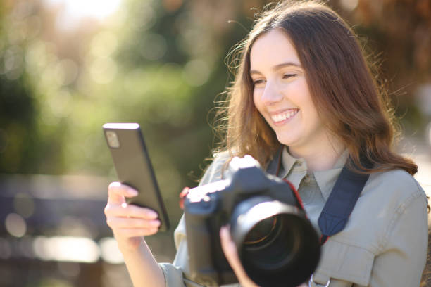istock Happy photographer holding camera and checking phone 1477088803