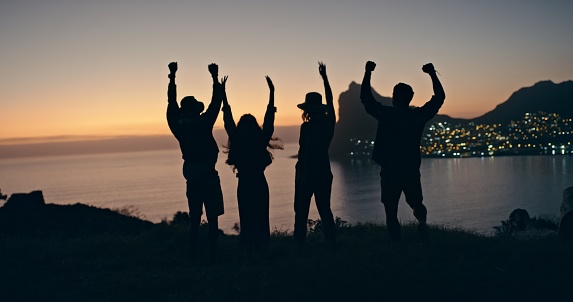 Friends, outdoor and silhouette with celebration, winning and victory with joy, cheerful and happiness. Women, men and people with trust, support and city lights with sunrise shadow and solidarity
