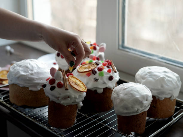 la main d’une femme caucasienne décore des gâteaux de pâques fraîchement cuits. cuisiner des gâteaux de pâques traditionnels faits maison - baking cake making women photos et images de collection