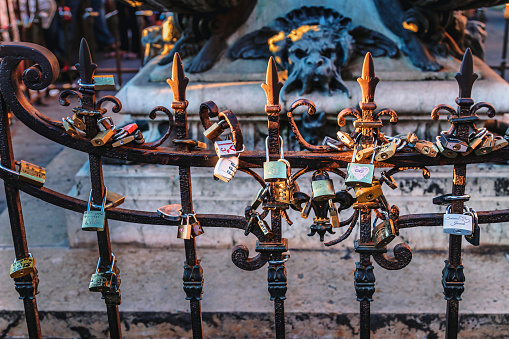 Florence, Italy - August 13, 2016:  Love locks in the evening light on Ponte Vecchio in Florence. Padlocks symbolizing eternal love can be found in iconic places all over Italy, and of course there are lots on the Ponte Vecchio in Florence Tuscany. Especially, on the railing of the statue of the goldsmith and sculptor Benvenuto Cellini which can seem as a bit of a paradox.