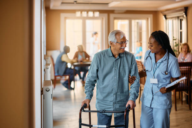 istock Happy black nurse assisting senior man in using mobility walker at nursing home. 1477094100