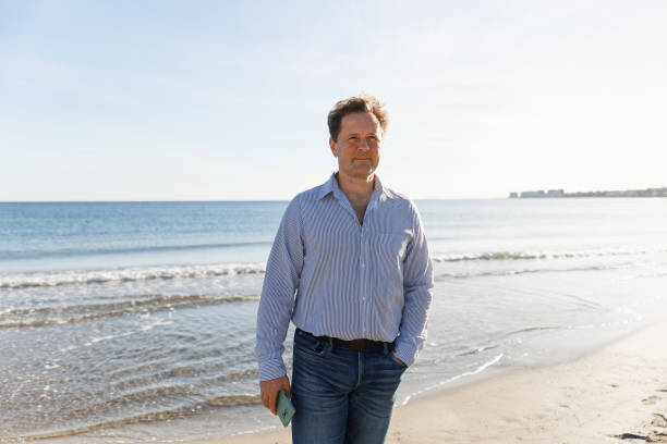 istock Businessman Talking On Phone, using smartphone mobile apps texting message, surfing social media tech standing on the city beach against the backdrop of the sea 1477094569