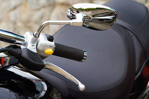Close-up view of motorcycle handle with switches and mirror