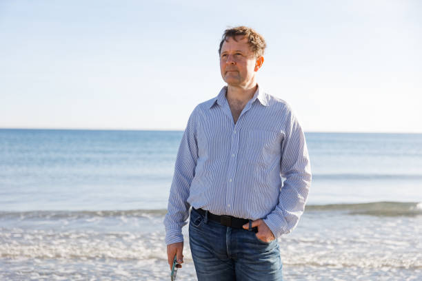 istock Businessman Talking On Phone, using smartphone mobile apps texting message, surfing social media tech standing on the city beach against the backdrop of the sea 1477095191