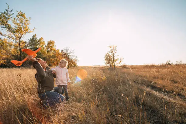 Photo of Happy Father And Child Having Fun Playing Outdoors. Smiling Young Dad And Daughter Spending Time Together, let an airplane into the sky