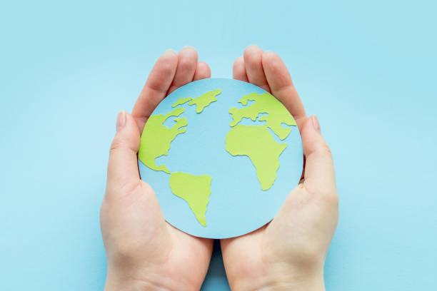 istock World environment day concept. Two human hands holding paper earth globe isolated over blue background 1477097300