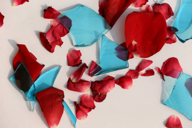 Broken Blue Glass With Red Rose Petals     isolated on white background Broken Blue Glass With Red Rose Petals     isolated on white background for concept of a broken relationship or marriage domestic violence india stock pictures, royalty-free photos & images