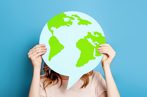 Earth day concept. Ecological problems of the globe, planet. Girl holding poster with earth paper layout isolated over blue background