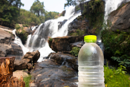 Water Bottle in front of Waterfall in a Forest Landscape