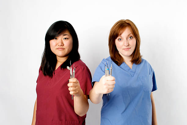 Medical Professionals holding dental tools Two Medical Professionals holding metal dental tools red medical scrubs stock pictures, royalty-free photos & images