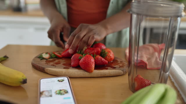 Close up of a woman slicing strawberries on a chopping board