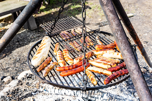 Grilled juicy sausages cooked on a campfire outdoors