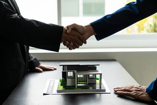 agent, lease, successful management\nReal estate brokerage manager shaking hands with client after signing home purchase contract in real estate agency office