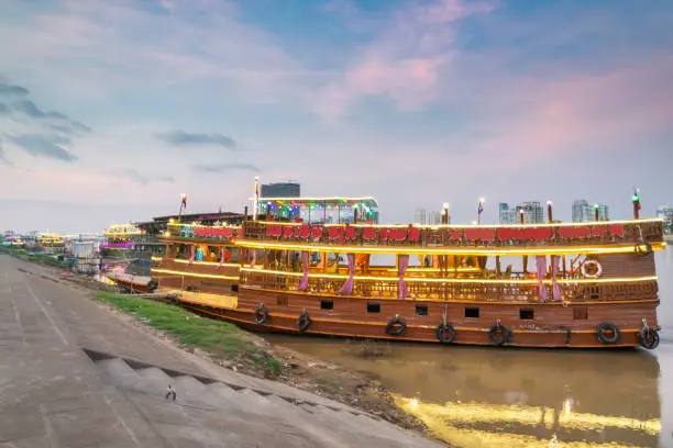 Colorfully lit at dusk,on the Riverside area of Phnom Penh,used as nightspots for tourists, eating and dancing,whilst touring,brightly lit, up and down the connected Tonle Sap and Mekong rivers.