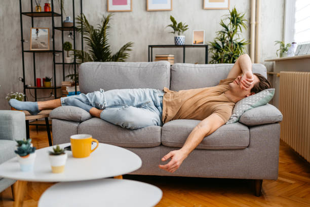 Young Man Sleeping On The Sofa At Home Handsome young man sleeping on the sofa at home. napping stock pictures, royalty-free photos & images