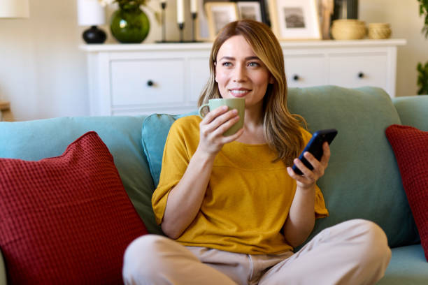 istock Woman using smartphone and drinking coffee at home in the morning 1477111168